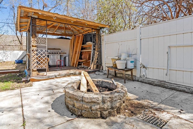 view of patio with a gazebo, a fire pit, fence, and grilling area