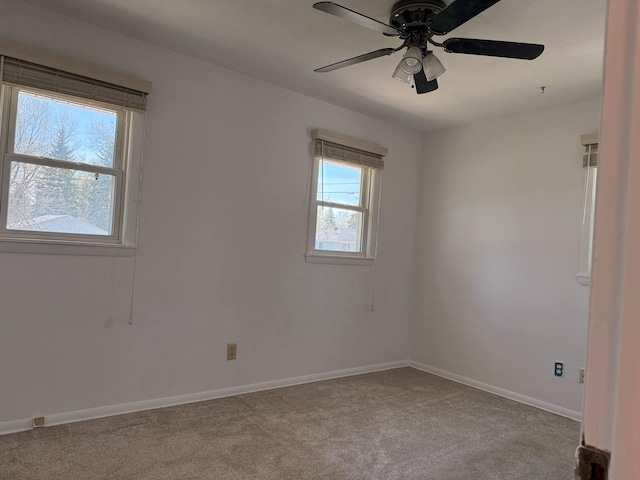 carpeted spare room featuring a ceiling fan and baseboards