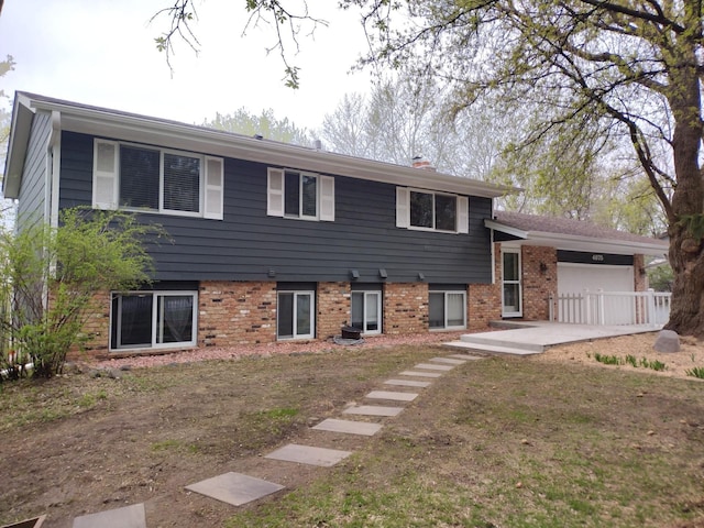 tri-level home featuring brick siding, a chimney, and a garage