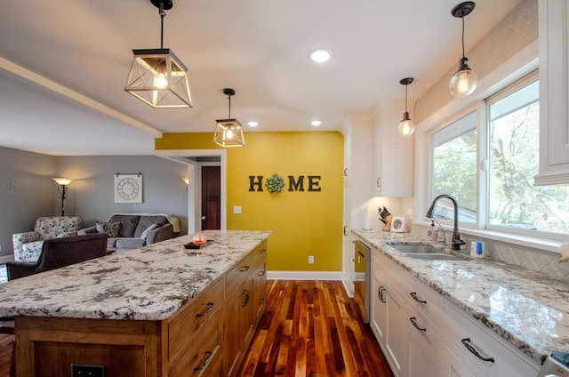 kitchen featuring a sink, white cabinetry, baseboards, dark wood-type flooring, and stainless steel dishwasher