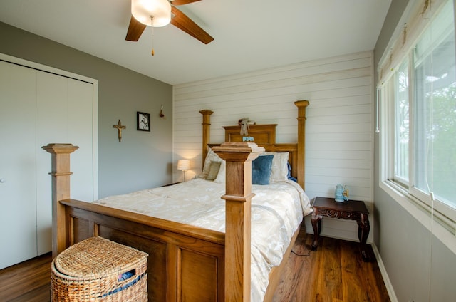 bedroom with multiple windows, wood walls, and dark wood-type flooring