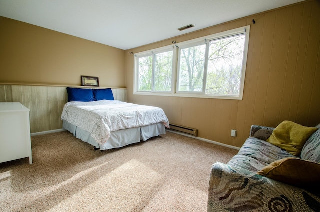 carpeted bedroom with visible vents, wood walls, baseboards, and a baseboard heating unit