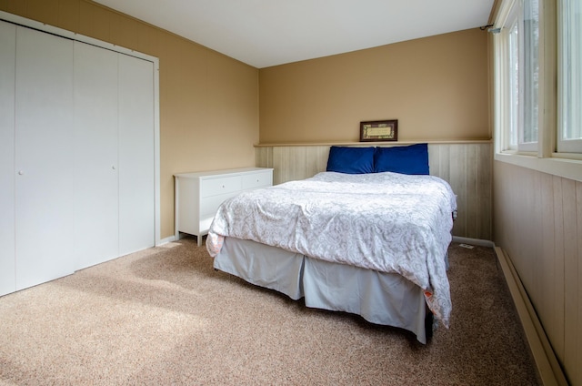 bedroom with carpet floors, wood walls, wainscoting, and a closet