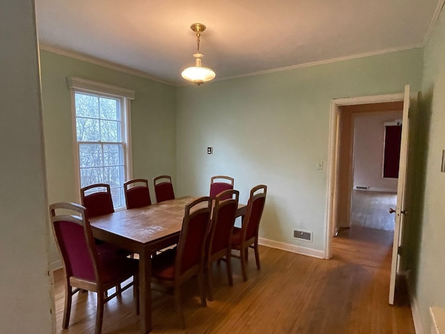 dining room with baseboards, ornamental molding, and light wood-style flooring