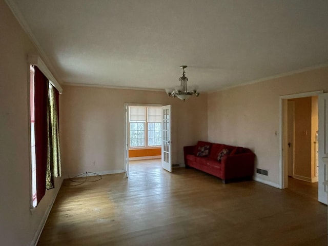 unfurnished room featuring visible vents, crown molding, wood finished floors, baseboards, and a chandelier