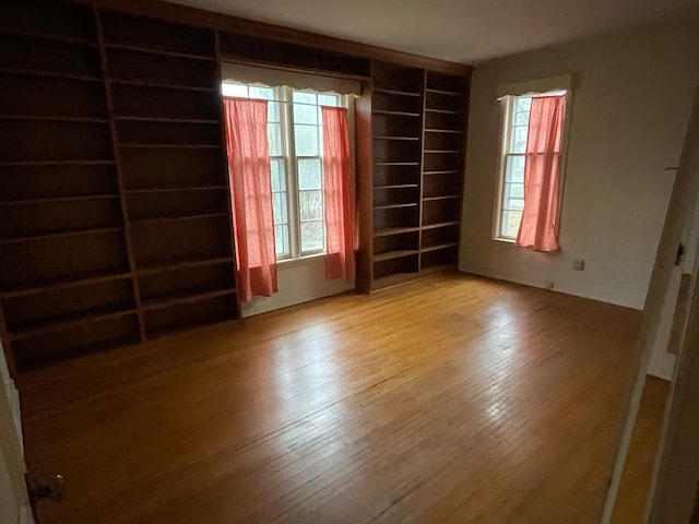 unfurnished room with wood-type flooring and built in features