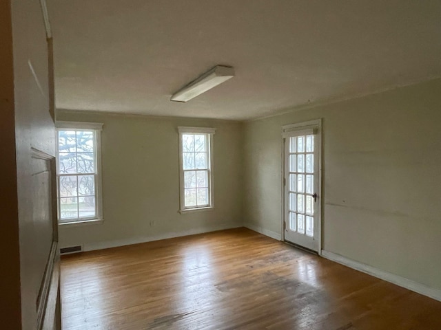 unfurnished room featuring baseboards, visible vents, and wood finished floors