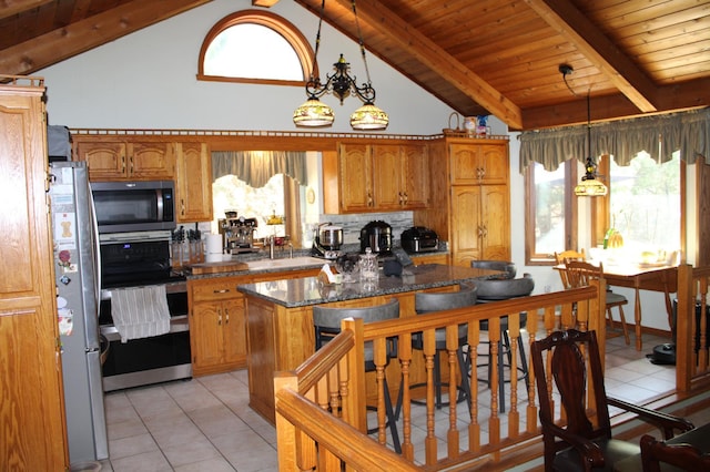 5795 Otter Lake Rd, White Bear Twp, MN 55110 - kitchen featuring appliances with stainless steel finishes, brown cabinetry, light tile patterned floors, hanging light fixtures, and backsplash