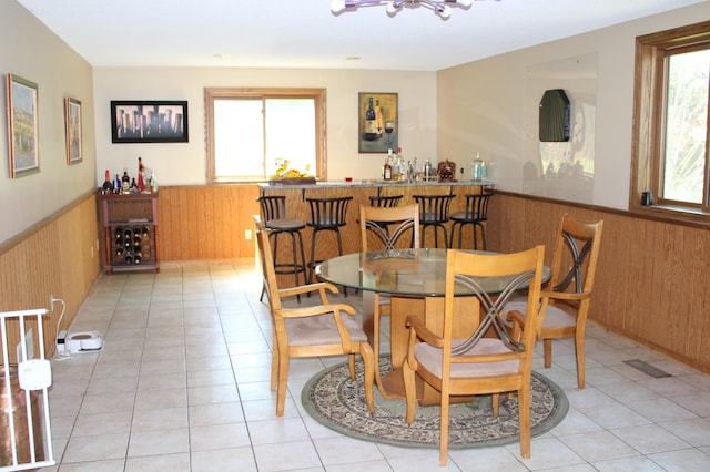 5795 Otter Lake Rd, White Bear Twp, MN 55110 - dining space featuring wainscoting, wood walls, light tile patterned flooring, and bar