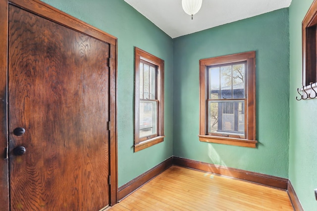 empty room with baseboards, light wood-style flooring, and a healthy amount of sunlight
