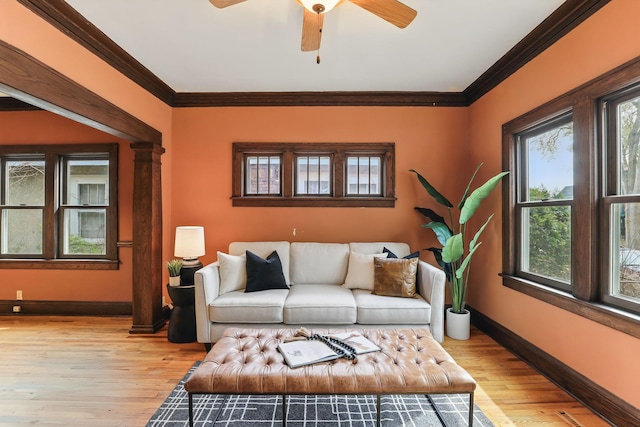 living area featuring light wood-style floors, baseboards, and crown molding