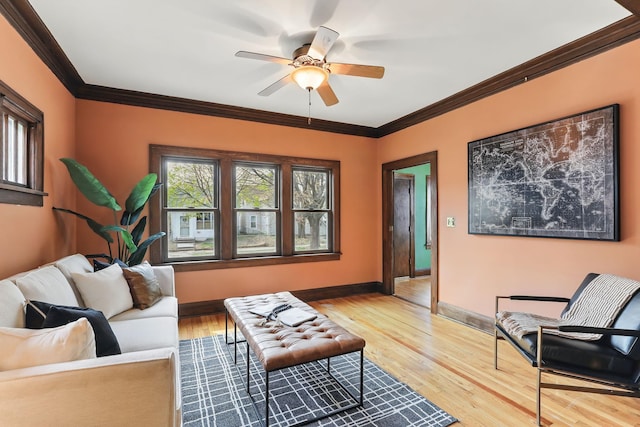 living area with crown molding, a ceiling fan, baseboards, and wood finished floors