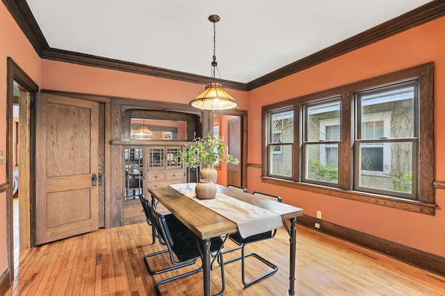 dining space with light wood-style floors, baseboards, and ornamental molding