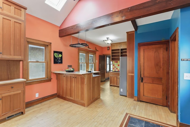 kitchen featuring freestanding refrigerator, a peninsula, a healthy amount of sunlight, and light wood-style floors