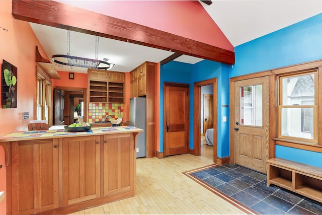 kitchen with vaulted ceiling with beams, freestanding refrigerator, light wood-style flooring, and a peninsula