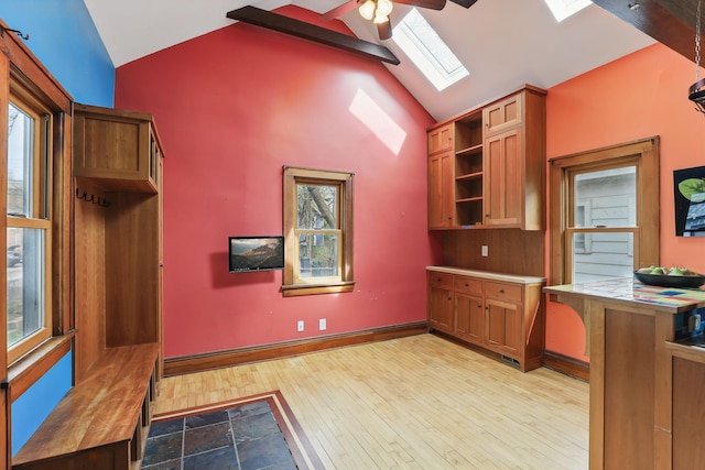 kitchen featuring a skylight, open shelves, brown cabinets, wood finished floors, and baseboards