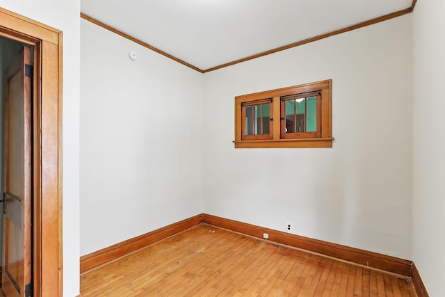 spare room with baseboards, ornamental molding, and light wood-style flooring