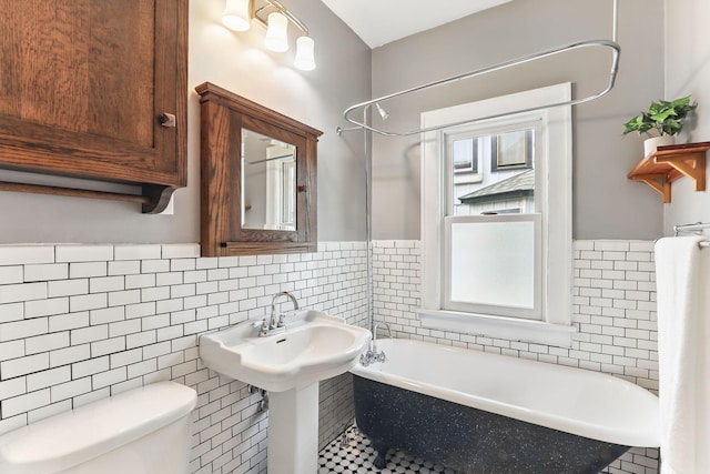 full bathroom featuring toilet, tile walls, bathtub / shower combination, and a wainscoted wall
