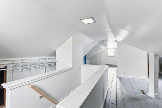 bonus room featuring visible vents, a baseboard radiator, lofted ceiling, and hardwood / wood-style floors