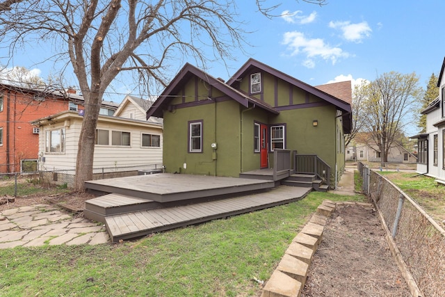 rear view of house featuring a fenced backyard, a wooden deck, stucco siding, and a lawn