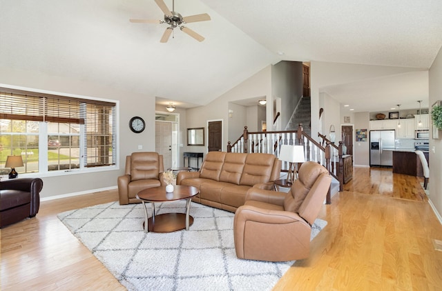 1006 9th Street Ct SE, New Prague, MN 56071 - living room featuring stairway, ceiling fan, light wood-type flooring, baseboards, and high vaulted ceiling