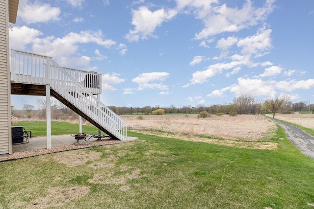 1006 9th Street Ct SE, New Prague, MN 56071 - view of grassy yard with stairway, a deck, a patio area, and a rural view