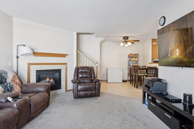 5085 149th St N # 3, Hugo, MN 55038 - living room featuring a ceiling fan, light colored carpet, a fireplace, stairway, and a textured ceiling