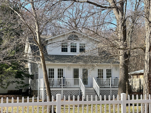 view of front of property featuring covered porch, a fenced front yard, and a shingled roof