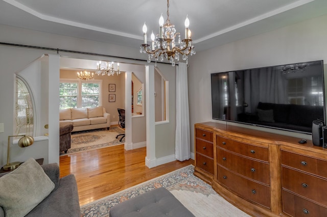 living room with an inviting chandelier, baseboards, and light wood-type flooring