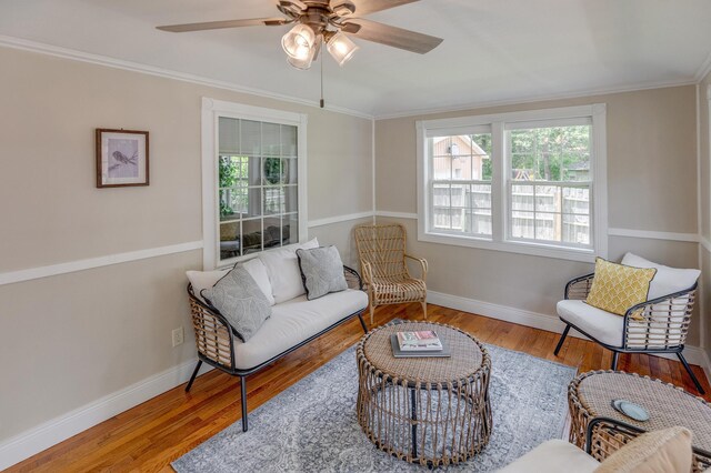 living room with baseboards, ceiling fan, ornamental molding, and wood finished floors