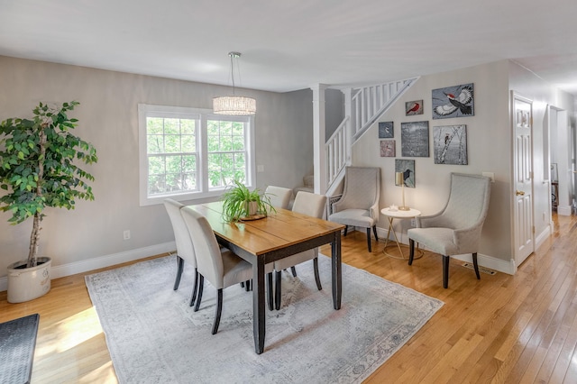 dining area with visible vents, baseboards, an inviting chandelier, stairs, and light wood-style flooring