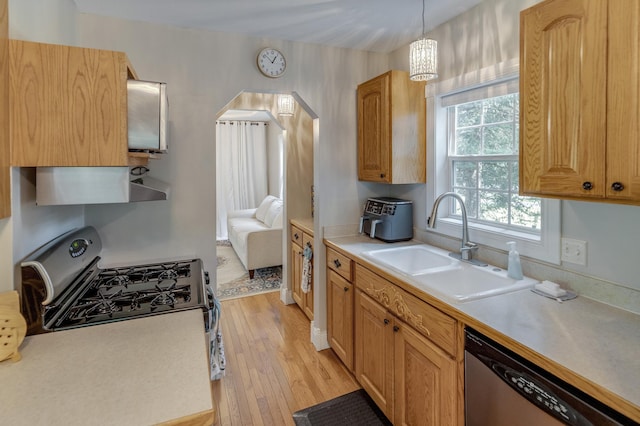 kitchen featuring light wood-type flooring, light countertops, under cabinet range hood, a sink, and stainless steel appliances