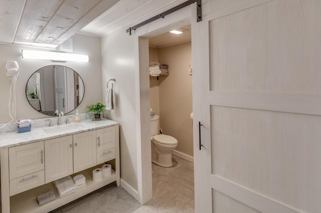 bathroom with vanity, baseboards, tile patterned floors, and toilet