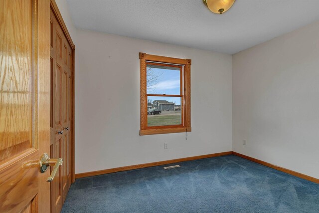 unfurnished room featuring baseboards, visible vents, and dark carpet