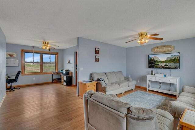 living area featuring baseboards, ceiling fan, and light wood-style flooring