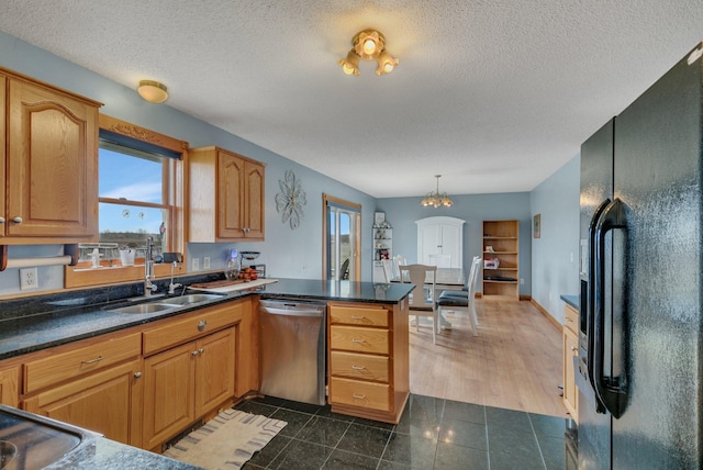 kitchen featuring a textured ceiling, stainless steel dishwasher, black fridge with ice dispenser, a sink, and a peninsula