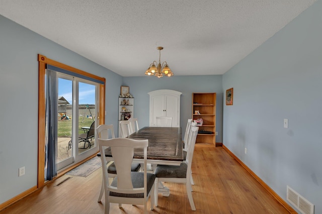 dining area featuring an inviting chandelier, baseboards, light wood-style flooring, and visible vents