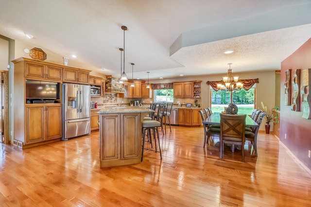 21005 County Highway 32, Rochert, MN 56578 - kitchen featuring appliances with stainless steel finishes, a chandelier, brown cabinetry, light wood-style floors, and a kitchen breakfast bar
