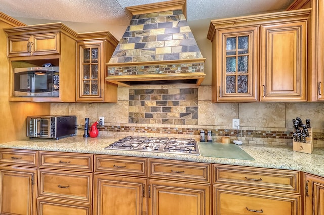 21005 County Highway 32, Rochert, MN 56578 - kitchen with stainless steel appliances, premium range hood, brown cabinets, decorative backsplash, and glass insert cabinets