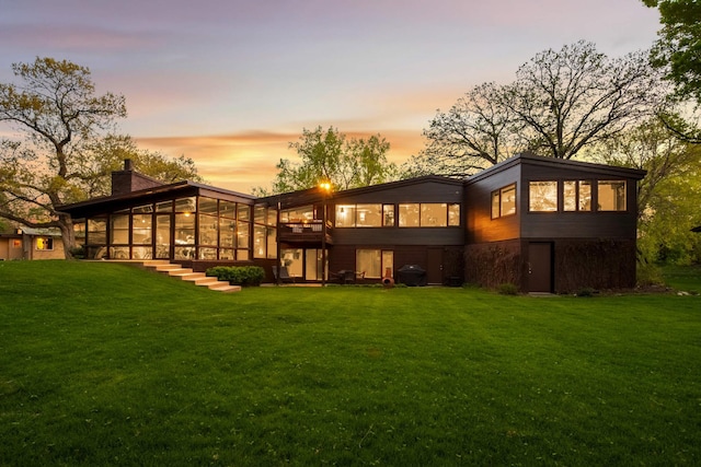 4618 Cedarwood Rd, Saint Louis Park, MN 55416 - back of house at dusk featuring a sunroom, a yard, and a chimney