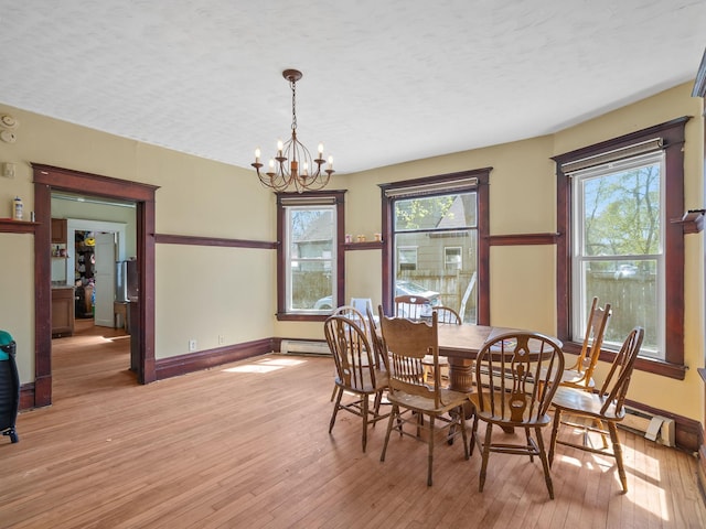 3213 Minnehaha Ave, Minneapolis, MN 55406 - dining room with a chandelier, light wood finished floors, a baseboard heating unit, and baseboards