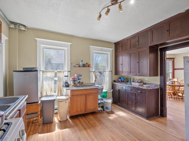 3213 Minnehaha Ave, Minneapolis, MN 55406 - kitchen with range, light wood-style floors, plenty of natural light, a textured ceiling, and a baseboard radiator