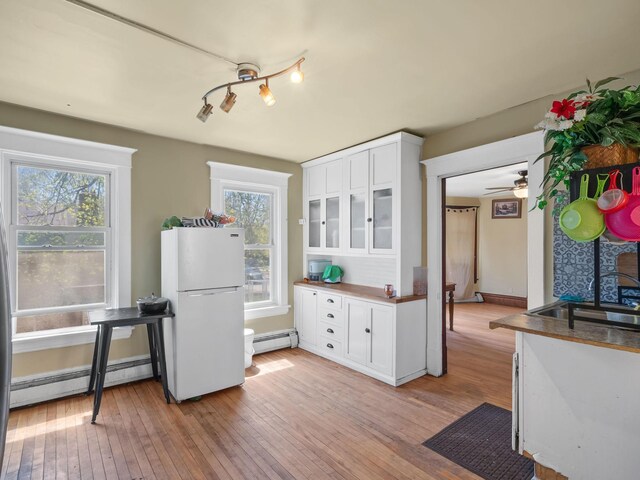 3213 Minnehaha Ave, Minneapolis, MN 55406 - kitchen featuring a baseboard heating unit, freestanding refrigerator, white cabinets, and light wood finished floors