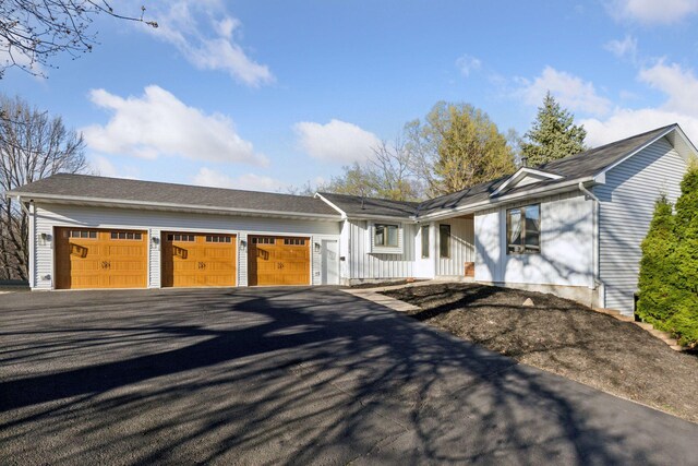 ranch-style home with a garage and aphalt driveway