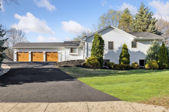 tri-level home with a garage, driveway, and a front yard