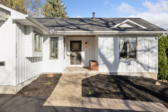 view of exterior entry featuring a shingled roof