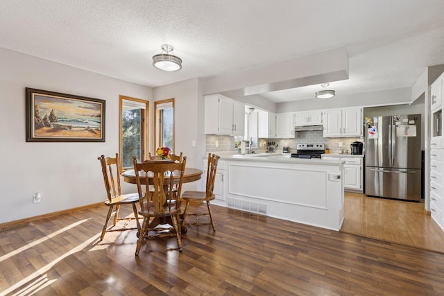 dining space featuring baseboards, a textured ceiling, wood finished floors, and visible vents