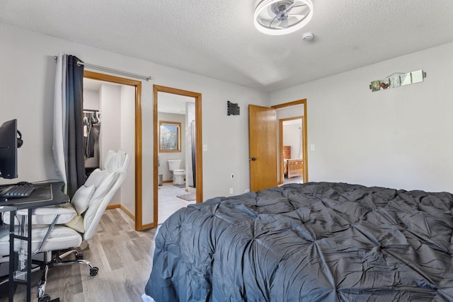 bedroom with ensuite bathroom, a textured ceiling, and light wood finished floors