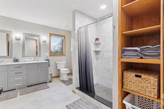 full bathroom featuring vanity, toilet, baseboards, tiled shower, and tile patterned floors