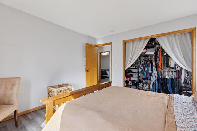 bedroom featuring baseboards, wood finished floors, and a closet